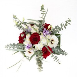 This bouquet, crafted by West Wickham florists, is a study in subtle contrast and unity-each element distinct yet woven together with the kind of thoughtful composition often found in community celebrations at Langley Park. The central roses, a deep velvety red, spiral outward in layers that speak of enduring affection and fond memory. Enveloping them, white gerbera daisies fan out with confidence, their rich brown hearts grounding the design and brightening the overall effect. Sprays of lilac lisianthus, some shy in bud and others opening to full bloom, add notes of contemporary freshness and unique charm. Fuffy clusters of white filler flowers read as gentle whispers between bolder stems, bestowing softness and dimension. Eucalyptus leaves drape gracefully over the bouquet, infusing it with a silvery-green shimmer and a distinct, calming scent-recalling local parks and forested corners of West Wickham. Broad, glossy green foliage binds the base, offering support and a polished finish. The transparent vase not only highlights the bouquet's fresh green stems but also enhances the sense of clarity and new beginnings. Perfect for anniversaries, new homes, or thoughtful gestures, it's a bouquet imbued with the welcoming spirit of the West Wickham community.